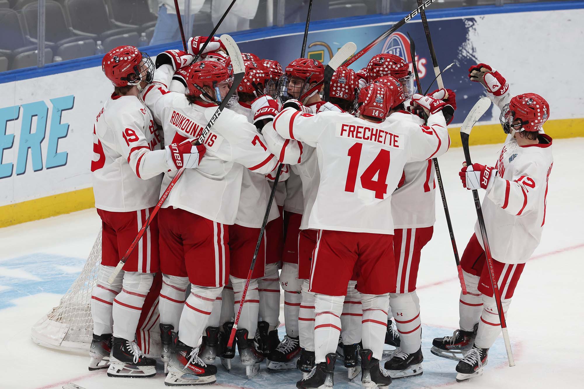 Photo: A celebratory huddle of BU hockey players on the ice