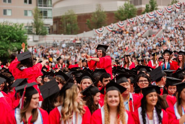Photo: Two students pointing at each other in a crowd during BU's Commencement