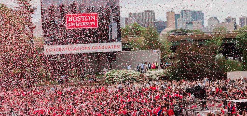 Photo: A wide shot of Nickerson Filed with confetti flying in the air. The large video board reads BOSTON UNIVERSITY CONGRATULATIONS GRADUATES!