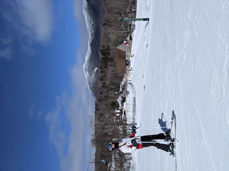 A skiier on a ski slope on a sunny day