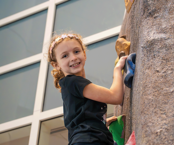 A child smiles on the climbing wall