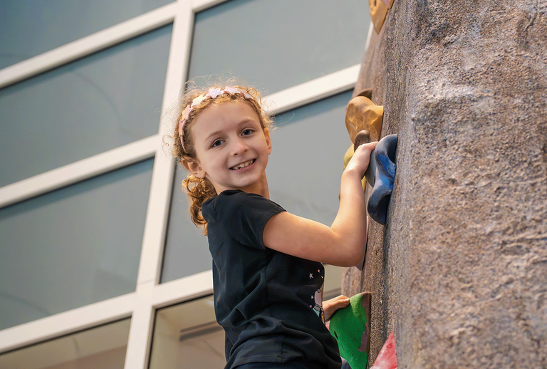 A child smiles on the climbing wall