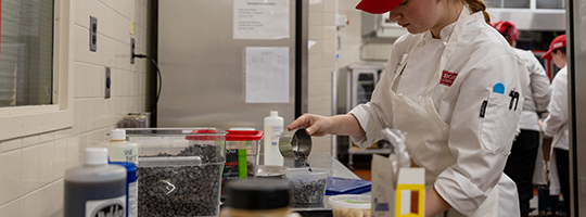 A student measuring baking ingredients on a food scale
