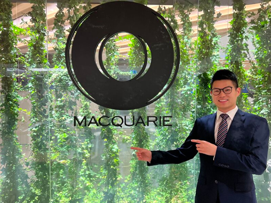 Andre Lo pointing to a Macquarie logo on a glass wall