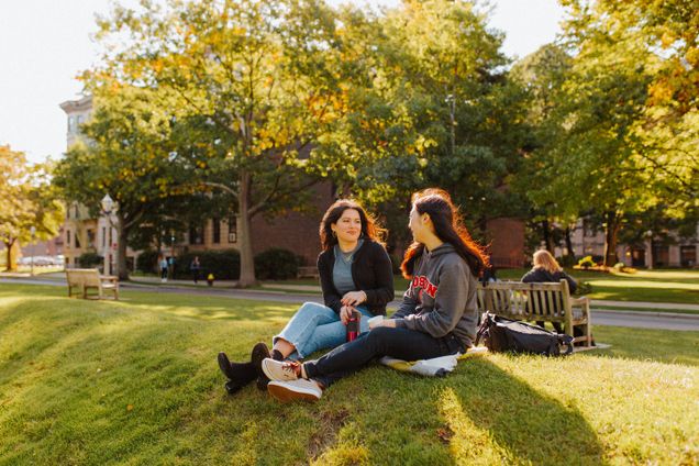 two students sitting on grass