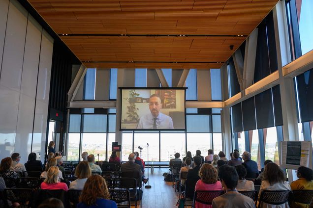 一个ttendees watch virtual remarks at the symposium