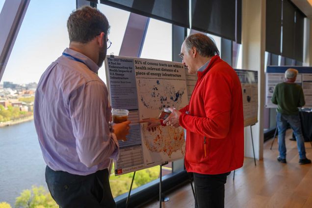 一个 student displays their poster at the symposium