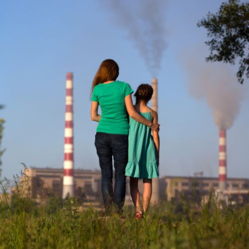 Woman and daughter standing in front of smokestacks
