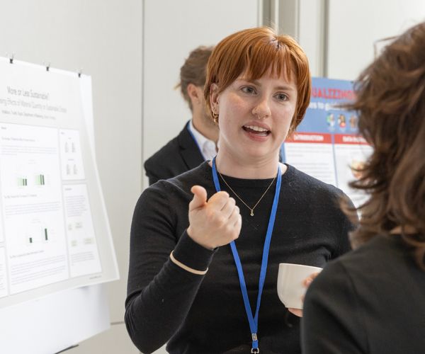 Researchers have a conversation in front of a poster.