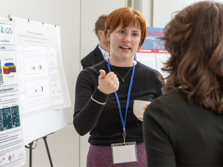 Researchers have a conversation in front of a poster.