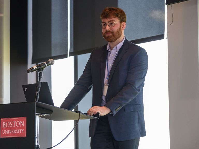 Professional stands in front of a microphone.