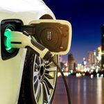 Electric vehicle charger with city skyline at night.