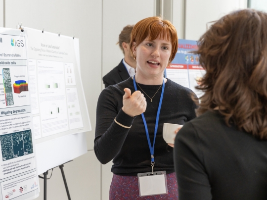 Two professionals speak at a research conference.