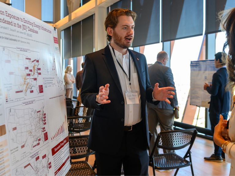 A professional talking in front of a research poster.