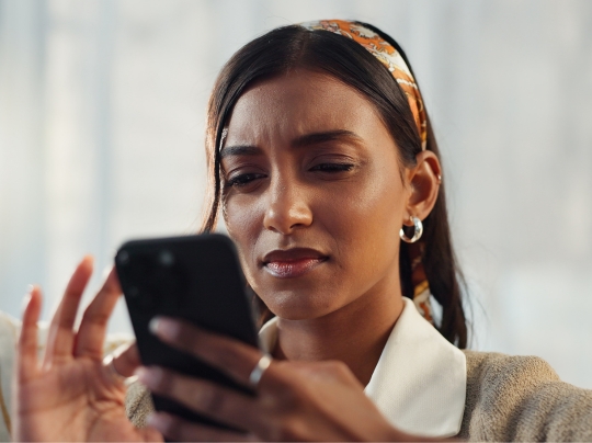 Woman scrolling online with doubtful expression.