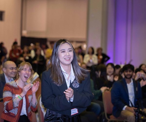 Woman smiling as she emerges from a large crowd at an event