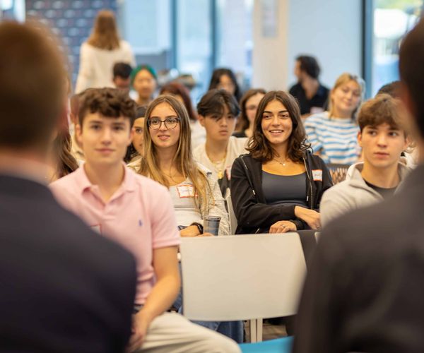 Group of students seated in the audience at an event and smiling