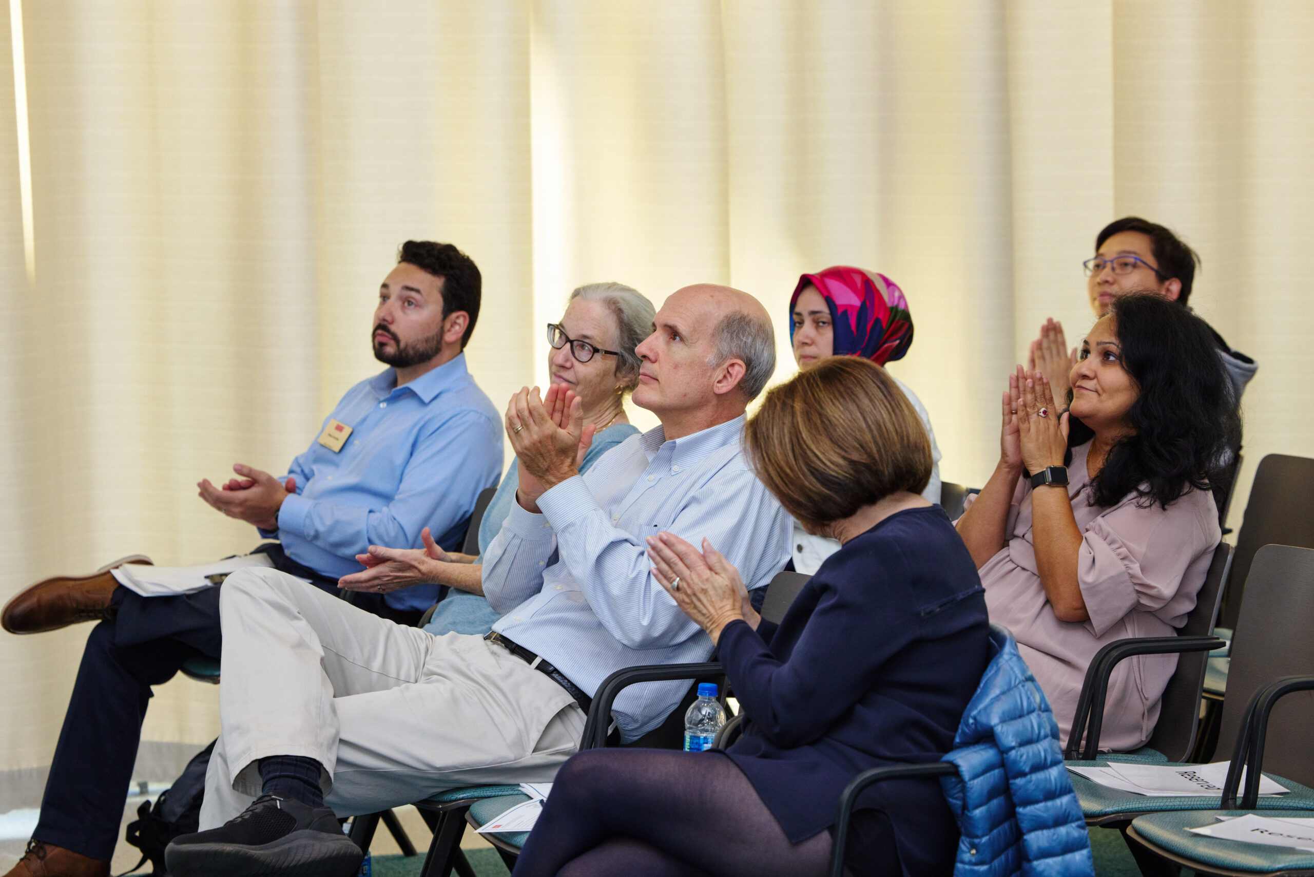 Audience members in colloquium room applauding