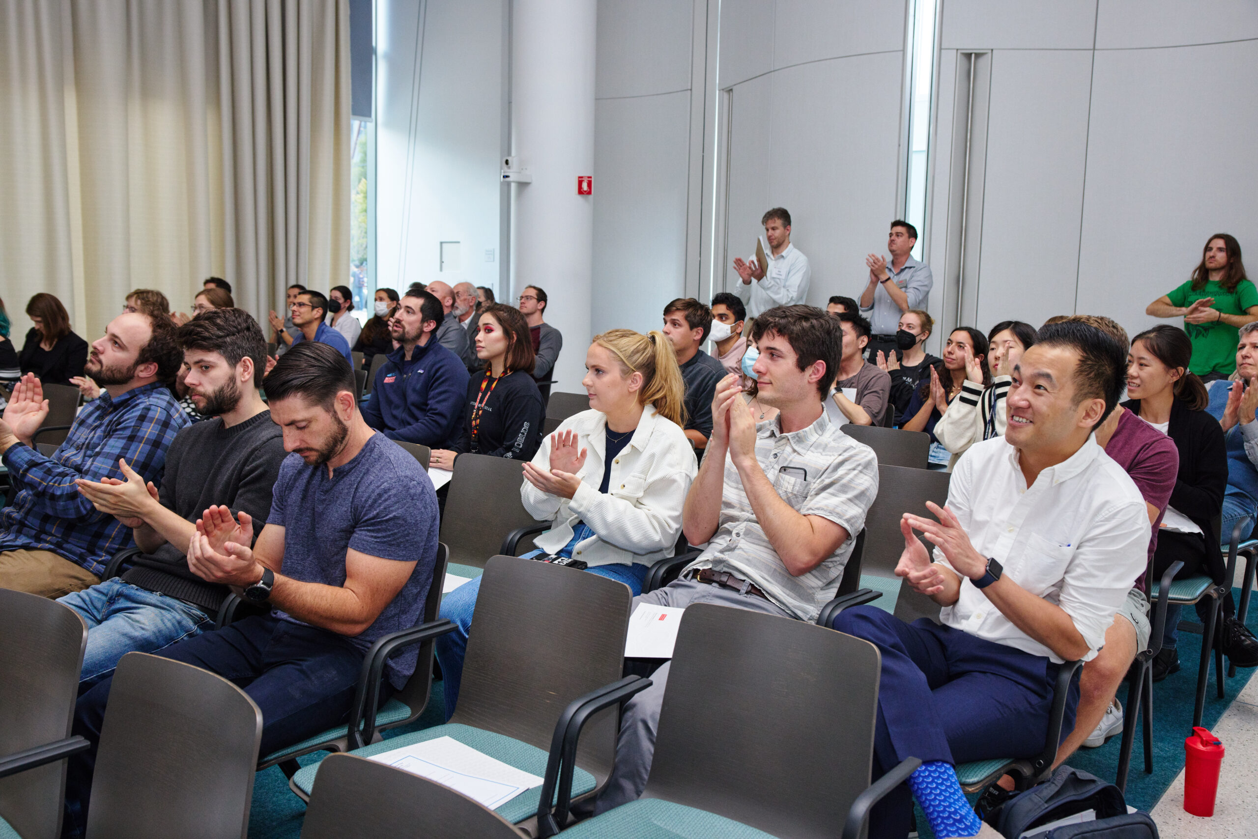 Seated audience in colloquium room applauding
