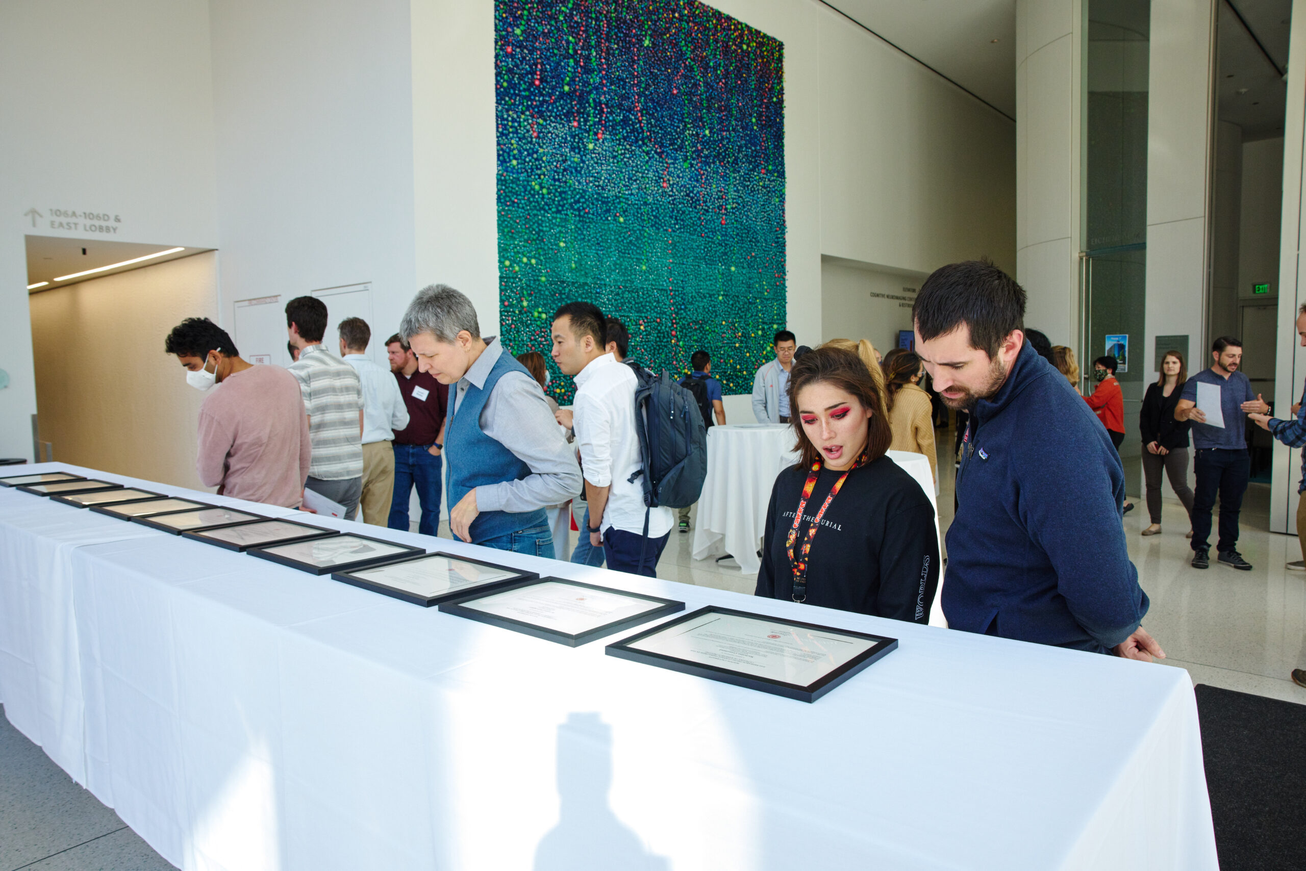 People looking at framed award certificates lying on a table