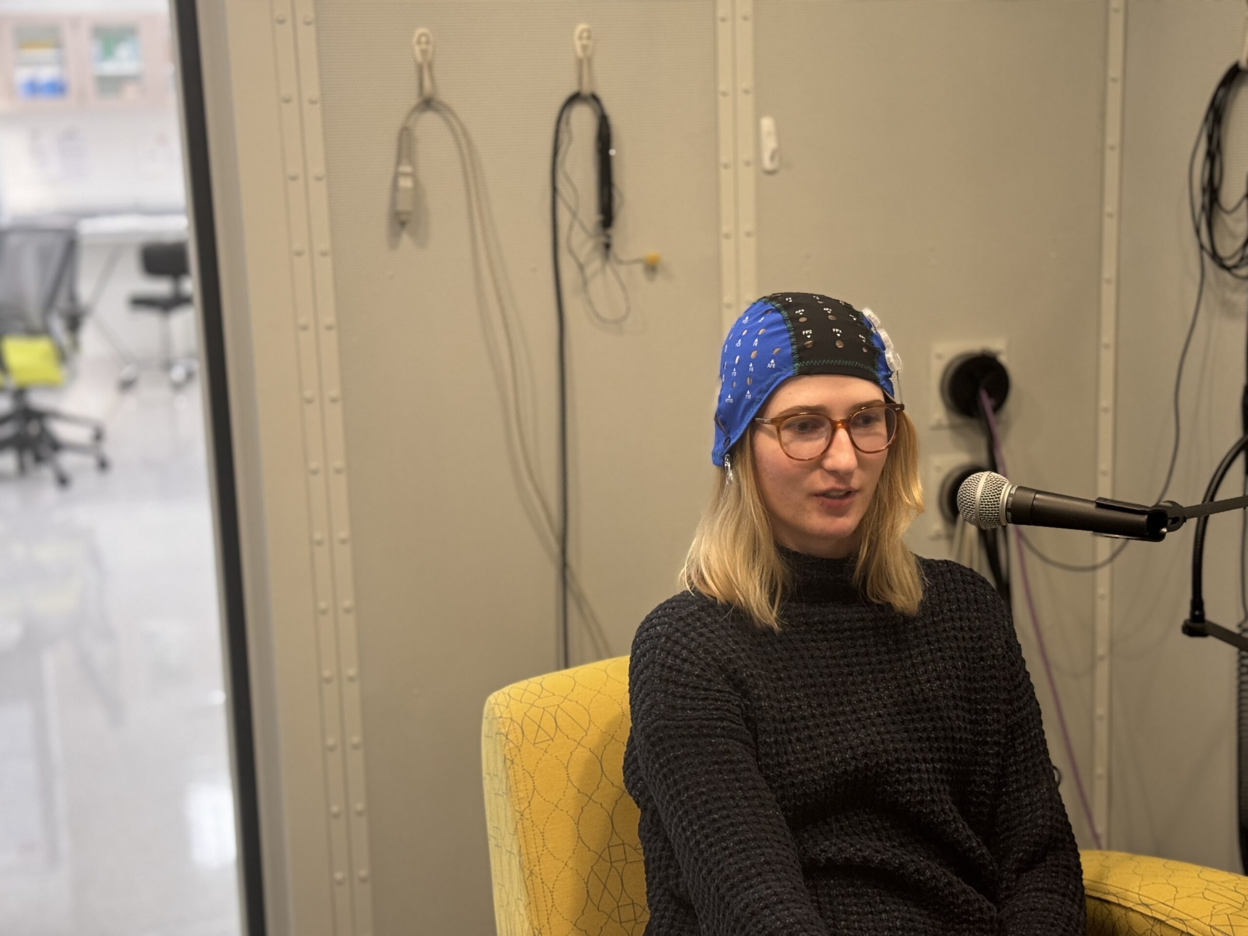 person sitting in sound booth and wearing experimental headgear