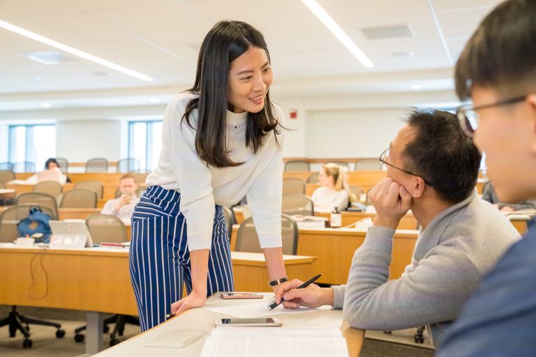 School of law professor engaging with two male students in a lecture hall