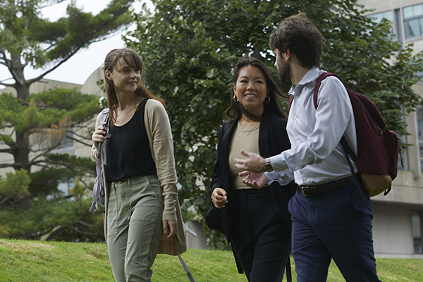 Three students discuss scholarships on a walk outside.
