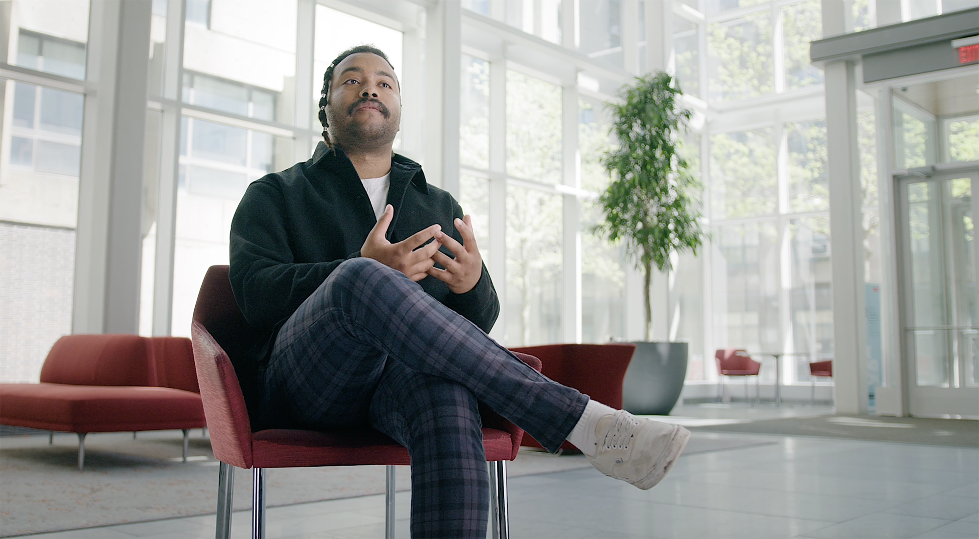 A BU Law student sits for an interview in the atrium of the law complex.