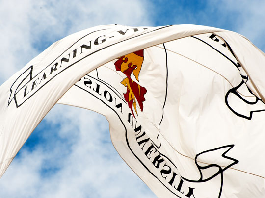 A Boston University flag flying in the breeze on campus - learn more about Tuition and Fees.