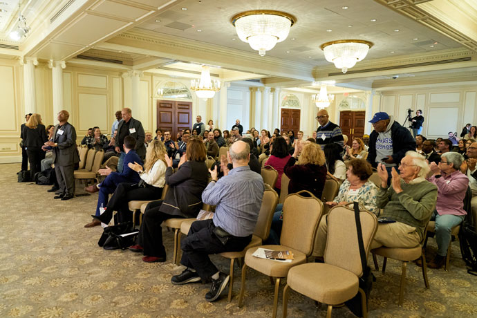 Audience members applauding at a conference event in a large room