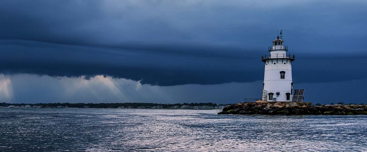 A lighthouse confronts a brewing storm