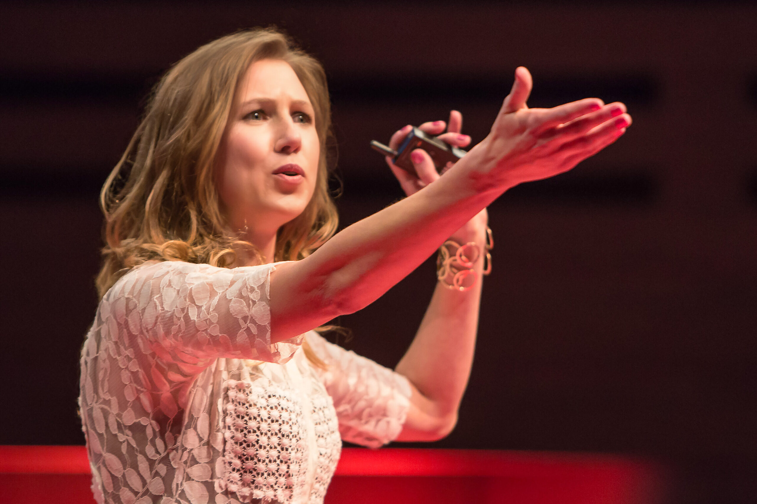 Speaker holding a remote in one hand, with other arm outstretched during speech