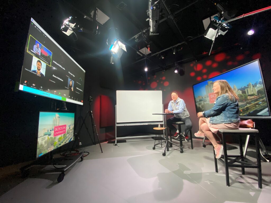 Online MBA lecture studio with professor and guest lecturer facing the screen where students listen in