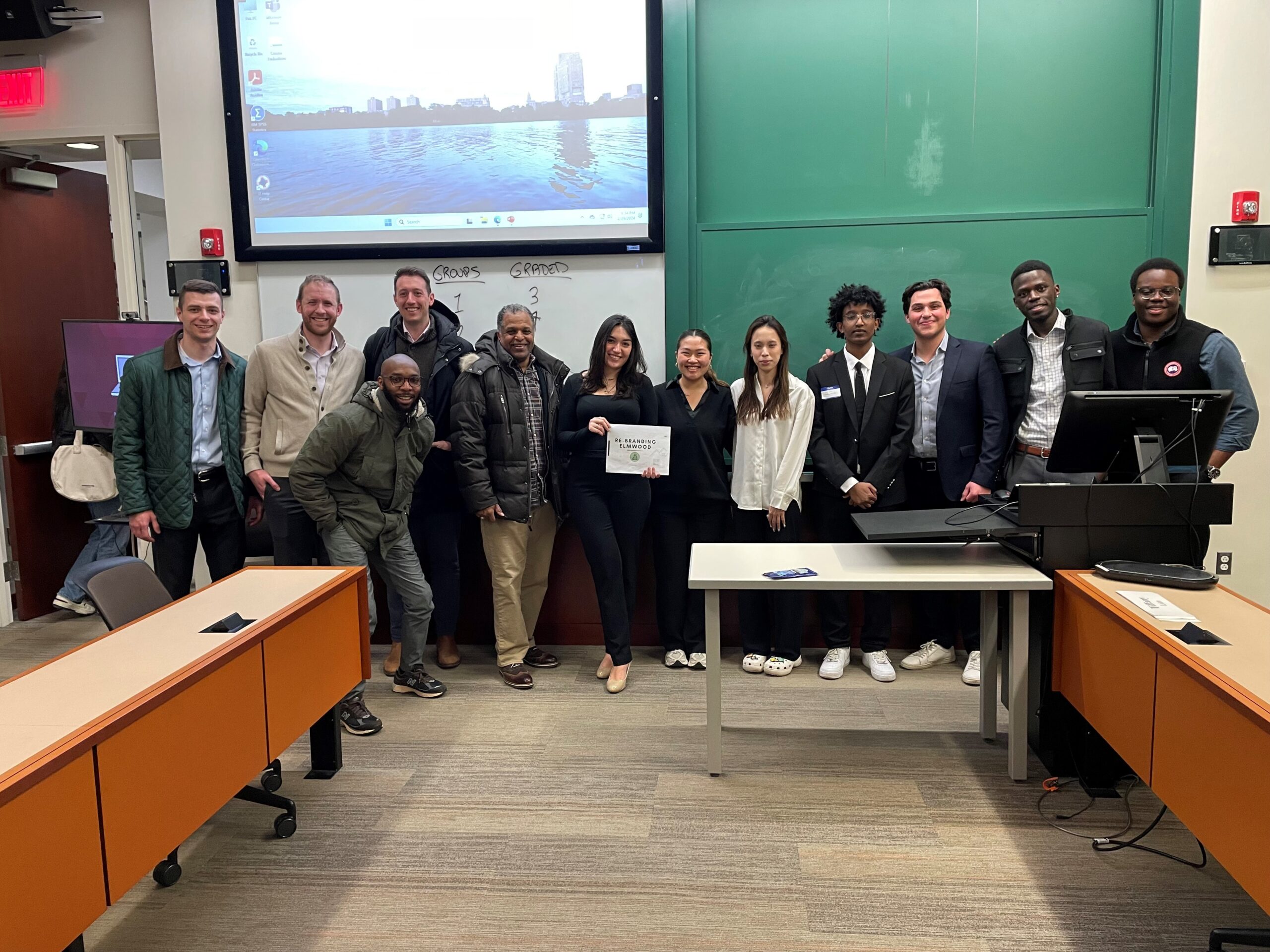 Students pose in the front of the classroom, woman student in center holds a certificate
