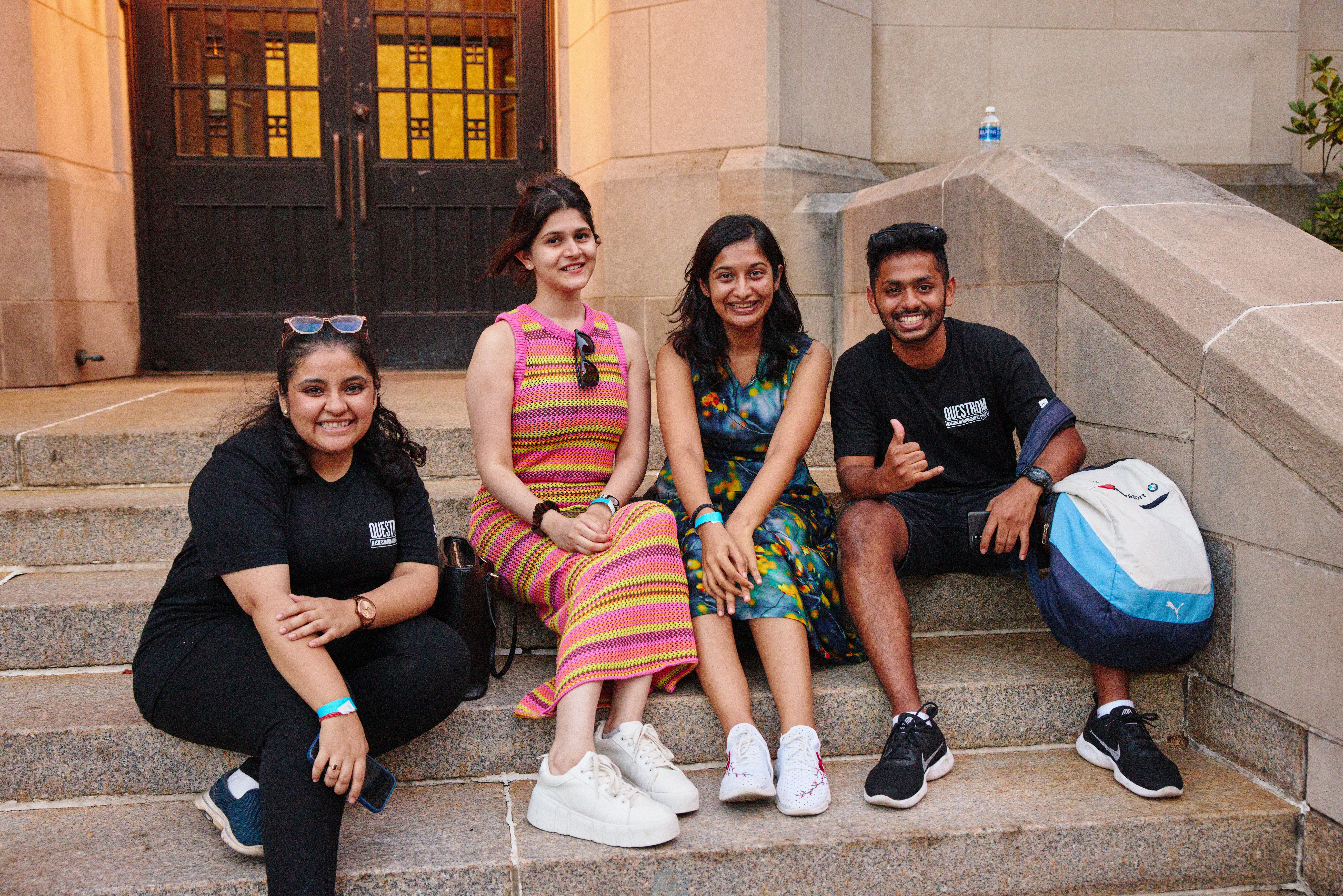 Four grad students sit and talk on the steps of Marsh Chapel