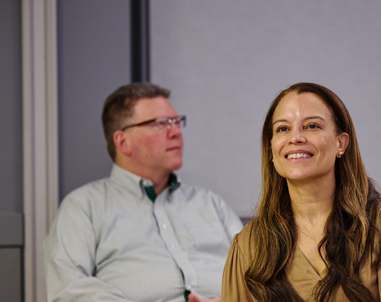 Women sits in classroom with an engaging smile.