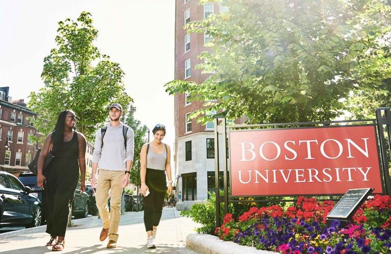 Students walking on BU campus in front of Boston University sign