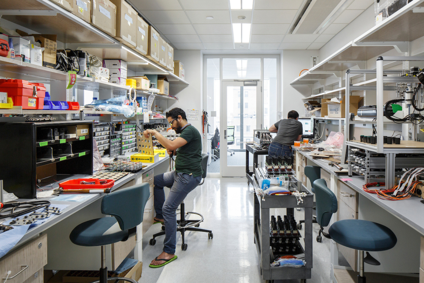 several people sit at lab benches working on instruments.