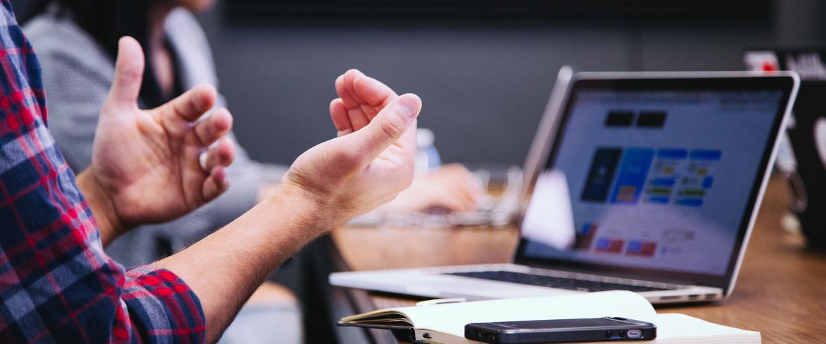 Person gesturing in front of a laptop