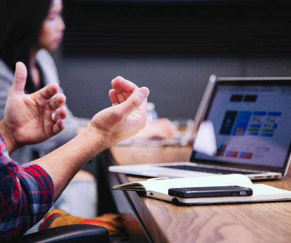 Person gesturing in front of a laptop