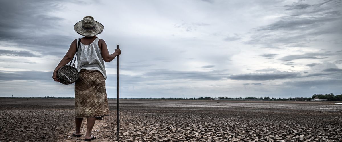Woman standing on dry soil in fishing gear