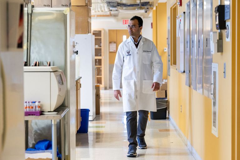 Virologist Mohsan Saeed walking down a laboratory hallway