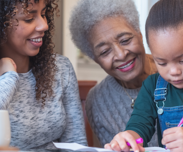 Little child coloring while sitting on grandmother's lap