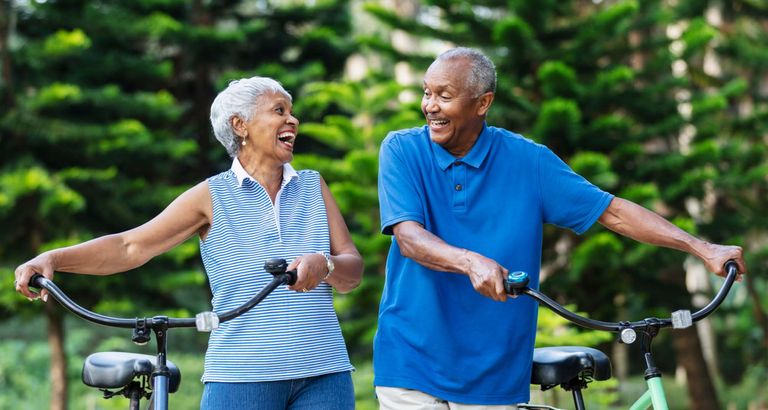 An elderly couple happily rides bikes