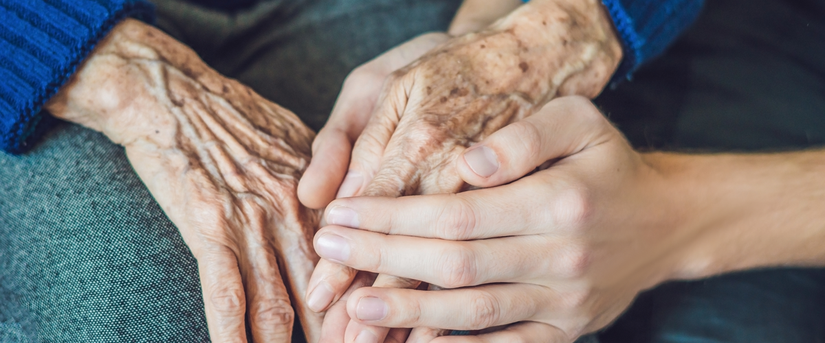 Young woman holding elderly woman's hand