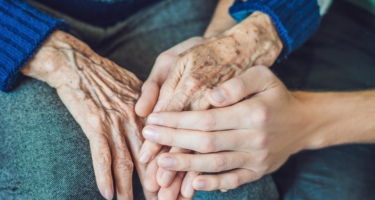Young woman holding elderly woman's hand