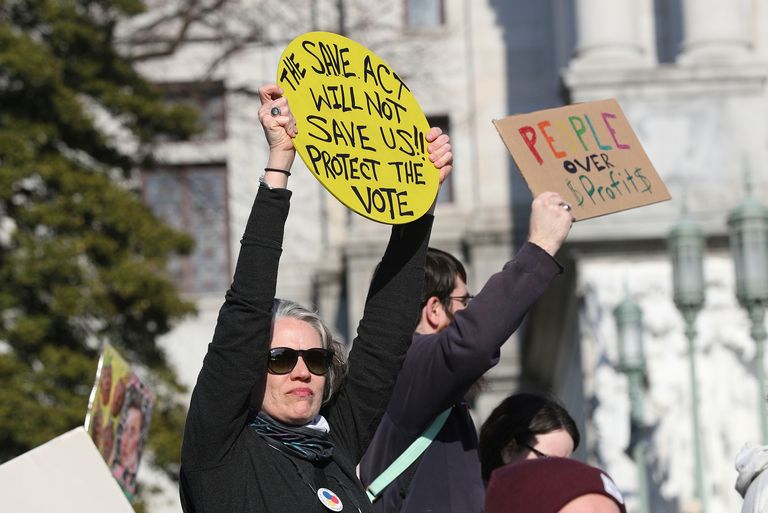 A protester outside the Pennsylvania State Capitol in Harrisburg, Pa., decries a new voting reform bill, the SAVE Act