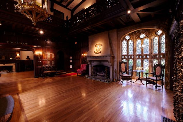 Empty room view of the Great Hall with hardwood floors, fireplace with BU emblem on it.