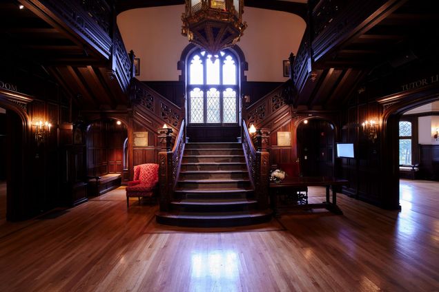View of staircase leading up to picturesque window with dark wood railings.