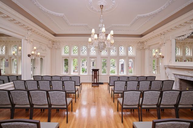 Music Room setup lecture style with grey fabrics chairs setup in rows with a wooden podium at the front.